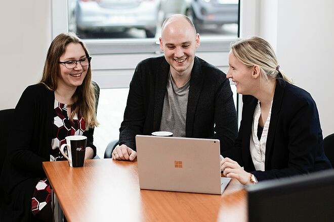 Drei Kollegen von ttp sitzen vor einem Laptop