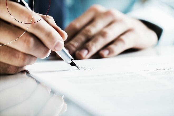 Hand unterschreibt ein Dokument mit Füller