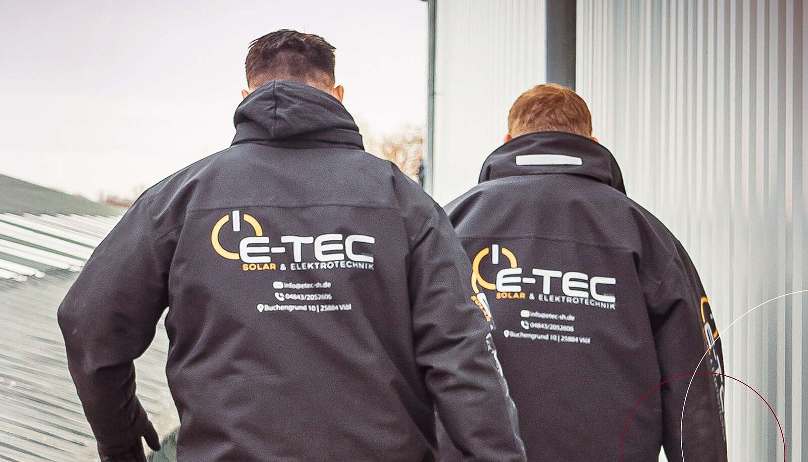 Zwei Männer tragen Arbeitskleidung mit dem Logo von E-Tec – Solar- & Elektrotechnik