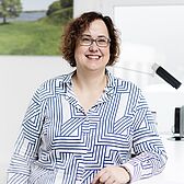 Sandra Gier, Teamleitung von ttp.lohn, steht an ihrem Schreibtisch, im Hintergrund hängt ein Landschaftsbild an der Wand