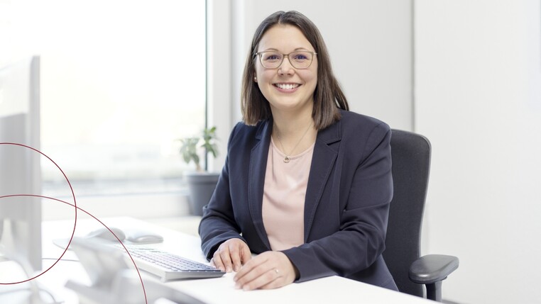 Headergrafik: Dr. Katharina Theis im Sitzen am Schreibtisch